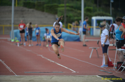 Eine Person streckt sich im Weitsprung in der Flugphase über der Sandgrube beim Walfried-Heinz-Sportfest der TG Konz im Saar-Mosel-Stadion in Konz.
