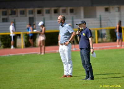 Zwei Verantwortliche stehen mit Mikrofon im Innenraum beim Walfried-Heinz-Sportfest der TG Konz im Saar-Mosel-Stadion in Konz.