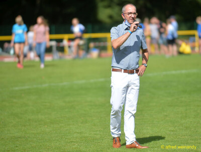 Eine Person spricht mit Mikrofon ins Publikum beim Walfried-Heinz-Sportfest der TG Konz im Saar-Mosel-Stadion in Konz.