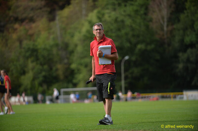 Eine Person im Kampfgericht mit Klemmbrett geht über den Sportplatz beim Walfried-Heinz-Sportfest der TG Konz im Saar-Mosel-Stadion in Konz.