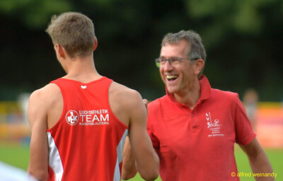 Zwei Personen unterhalten sich lachend am Rand des Wettkampfs beim Walfried-Heinz-Sportfest der TG Konz im Saar-Mosel-Stadion in Konz.