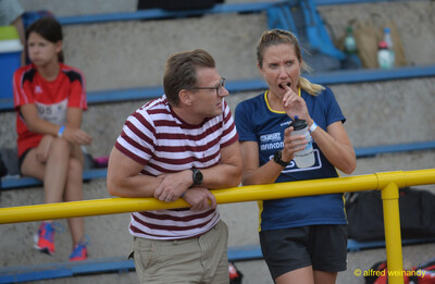 Zwei Personen stehen am Geländer, eine trinkt aus einer Flasche, beim Walfried-Heinz-Sportfest der TG Konz im Saar-Mosel-Stadion in Konz.