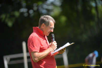 Eine Person an der Stadionansage verliest mit Mikrofon die Ergebnisse beim Walfried-Heinz-Sportfest der TG Konz im Saar-Mosel-Stadion in Konz.