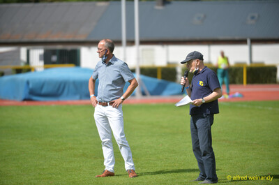 Zwei Verantwortliche begrüßen mit Mikrofon die Teilnehmenden auf dem Rasen beim Walfried-Heinz-Sportfest der TG Konz im Saar-Mosel-Stadion in Konz.