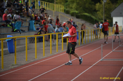 Eine Person im Kampfgericht überquert mit Startunterlagen die Laufbahn beim Walfried-Heinz-Sportfest der TG Konz im Saar-Mosel-Stadion in Konz.