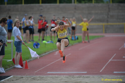 Eine junge Person fliegt beim Dreisprung in Richtung der Sandgrube, beim Walfried-Heinz-Sportfest der TG Konz im Saar-Mosel-Stadion in Konz.