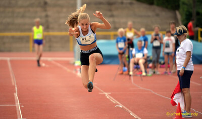 Eine junge Person in der Flugphase des Dreisprungs über der Anlaufbahn, beim Walfried-Heinz-Sportfest der TG Konz im Saar-Mosel-Stadion in Konz.