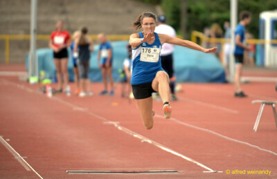 Eine Person streckt sich in der Flugphase des Dreisprungs über der Anlaufbahn, beim Walfried-Heinz-Sportfest der TG Konz im Saar-Mosel-Stadion in Konz.