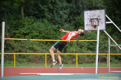 Eine Person im roten Trikot überquert in Flop-Technik die Latte beim Walfried-Heinz-Sportfest der TG Konz im Saar-Mosel-Stadion in Konz.