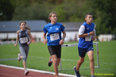 Drei Kinder laufen gemeinsam auf der Bahn beim Walfried-Heinz-Sportfest der TG Konz im Saar-Mosel-Stadion in Konz.