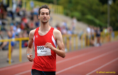Eine Person im roten Trikot läuft auf der roten Rundbahn beim Walfried-Heinz-Sportfest der TG Konz im Saar-Mosel-Stadion in Konz.