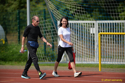 Zwei Personen gehen in Sportkleidung über die rote Laufbahn beim Walfried-Heinz-Sportfest der TG Konz im Saar-Mosel-Stadion in Konz.