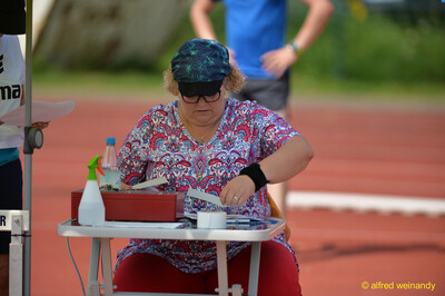 Eine Person im Helferdienst sitzt am Wettkampftisch und sortiert Unterlagen beim Walfried-Heinz-Sportfest der TG Konz im Saar-Mosel-Stadion in Konz.