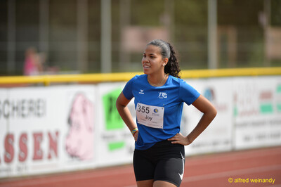 Eine junge Person steht mit Händen in den Hüften am Bahnrand beim Walfried-Heinz-Sportfest der TG Konz im Saar-Mosel-Stadion in Konz.