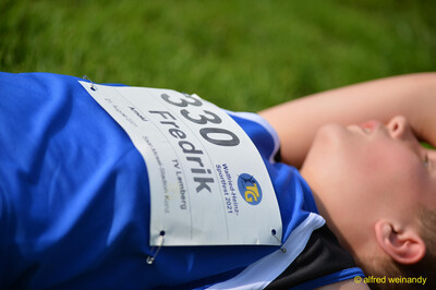 Nahaufnahme einer Startnummer auf dem Trikot einer im Gras liegenden Person beim Walfried-Heinz-Sportfest der TG Konz im Saar-Mosel-Stadion in Konz.