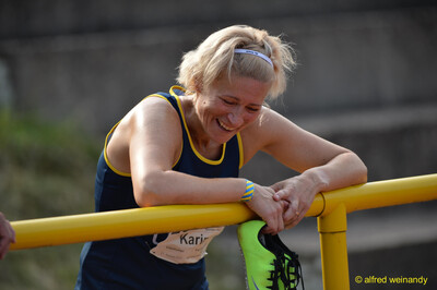 Eine Person lehnt fröhlich an einer gelben Absperrung und hält ihre Spikes beim Walfried-Heinz-Sportfest der TG Konz im Saar-Mosel-Stadion in Konz.
