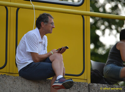 Eine Person im Kampfgericht macht eine Pause am Rand des Geschehens beim Walfried-Heinz-Sportfest der TG Konz im Saar-Mosel-Stadion in Konz.