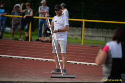 Eine Person steht mit einem Bahn-Abzieher auf der Laufbahn beim Walfried-Heinz-Sportfest der TG Konz im Saar-Mosel-Stadion in Konz.
