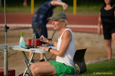 Eine Person im Kampfgericht notiert Ergebnisse am Wettkampftisch beim Walfried-Heinz-Sportfest der TG Konz im Saar-Mosel-Stadion in Konz.