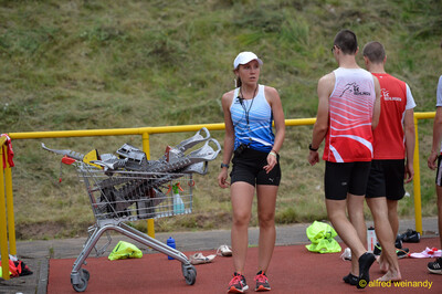 Eine Person mit Kappe und Trillerpfeife geht neben einem Einkaufswagen voller Spikes, daneben mehrere Aktive, beim Walfried-Heinz-Sportfest der TG Konz im Saar-Mosel-Stadion in Konz