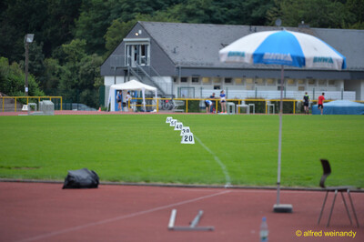 Blick über die leere Wettkampfanlage mit Weiten-Markierungen und Sonnenschirm beim Walfried-Heinz-Sportfest der TG Konz im Saar-Mosel-Stadion in Konz