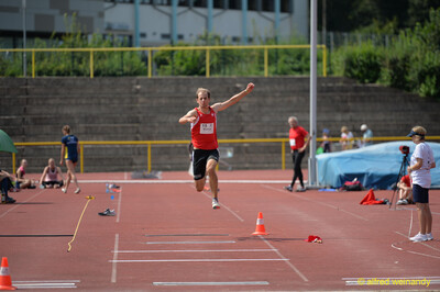 Eine Person schwebt in der Sprungphase über der Dreisprunganlage beim Walfried-Heinz-Sportfest der TG Konz im Saar-Mosel-Stadion in Konz.