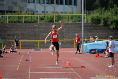 Eine Person fliegt in einer Sprungphase über die Dreisprunganlage beim Walfried-Heinz-Sportfest der TG Konz im Saar-Mosel-Stadion in Konz.