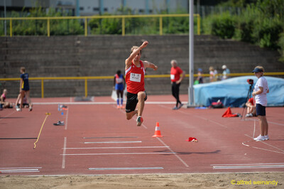 Eine Person befindet sich in der Sprungphase über der Dreisprunganlage mit der Sandgrube im Vordergrund beim Walfried-Heinz-Sportfest der TG Konz im Saar-Mosel-Stadion in Konz.