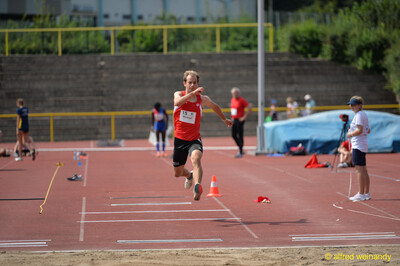 Eine Person in dynamischer Schrittphase über der Dreisprunganlage beim Walfried-Heinz-Sportfest der TG Konz im Saar-Mosel-Stadion in Konz.