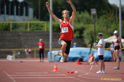 Eine Person streckt in der Flugphase beide Arme nach oben, beim Walfried-Heinz-Sportfest der TG Konz im Saar-Mosel-Stadion in Konz.