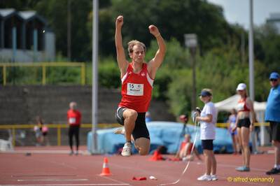 Eine Person schwingt in hoher Flugphase beide Arme über den Kopf, beim Walfried-Heinz-Sportfest der TG Konz im Saar-Mosel-Stadion in Konz.