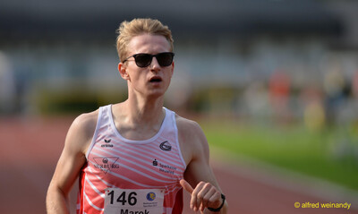 Eine Person läuft mit Sonnenbrille konzentriert über die Laufbahn beim Walfried-Heinz-Sportfest der TG Konz im Saar-Mosel-Stadion in Konz.