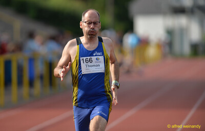 Eine Person läuft angestrengt mit Startnummer über die Laufbahn beim Walfried-Heinz-Sportfest der TG Konz im Saar-Mosel-Stadion in Konz.