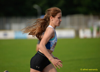 Eine Person läuft im Profil mit wehenden Haaren über die Laufbahn beim Walfried-Heinz-Sportfest der TG Konz im Saar-Mosel-Stadion in Konz.