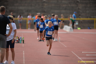 Ein Kind sprintet lächelnd über die Laufbahn, weitere Kinder warten im Hintergrund, beim Walfried-Heinz-Sportfest der TG Konz im Saar-Mosel-Stadion in Konz.