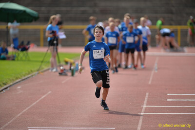 Ein Kind sprintet allein mit vollem Einsatz über die Rundbahn auf die Ziellinie zu beim Walfried-Heinz-Sportfest der TG Konz im Saar-Mosel-Stadion in Konz.