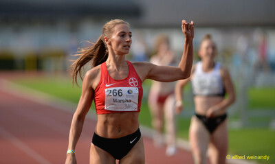 Eine Person hebt nach dem Zieleinlauf auf der Tartanbahn den Arm beim Walfried-Heinz-Sportfest der TG Konz im Saar-Mosel-Stadion in Konz.