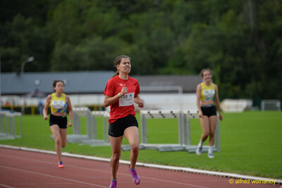 Eine Person im roten Shirt erreicht angestrengt das Ziel auf der Rundbahn beim Walfried-Heinz-Sportfest der TG Konz im Saar-Mosel-Stadion in Konz.