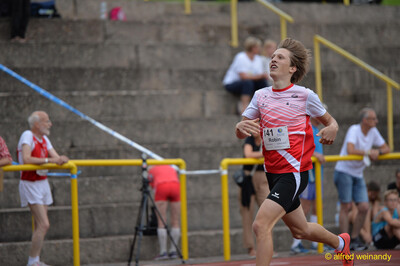 Ein Kind im rot-weißen Trikot mit der Startnummer 141 sprintet über die Rundbahn beim Walfried-Heinz-Sportfest der TG Konz im Saar-Mosel-Stadion in Konz.