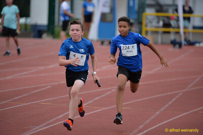 Zwei Kinder sprinten mit dem Staffelstab über die Bahn beim Walfried-Heinz-Sportfest der TG Konz im Saar-Mosel-Stadion in Konz.