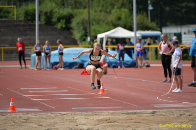Eine Person zieht beim Weitsprung in der Flugphase die Knie an, kurz vor der Sandgrube beim Walfried-Heinz-Sportfest der TG Konz im Saar-Mosel-Stadion in Konz.