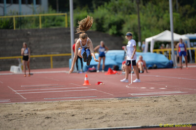 Eine Person schwebt in der Flugphase mit ausgestreckten Armen über der Sandgrube beim Walfried-Heinz-Sportfest der TG Konz im Saar-Mosel-Stadion in Konz.