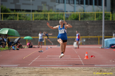 Eine Person schwingt in der Flugphase eines Weitsprungs die Arme nach oben beim Walfried-Heinz-Sportfest der TG Konz im Saar-Mosel-Stadion in Konz.
