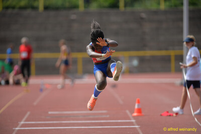 Eine Person hoch in der Flugphase des Weitsprungs mit angezogenem Bein beim Walfried-Heinz-Sportfest der TG Konz im Saar-Mosel-Stadion in Konz.