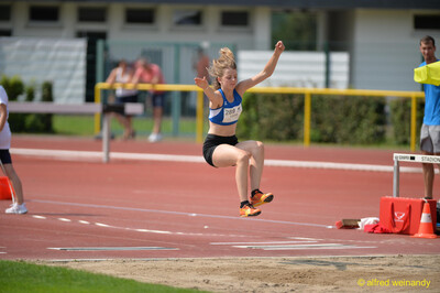 Eine junge Person schwebt in der Flugphase über der Sandgrube beim Walfried-Heinz-Sportfest der TG Konz im Saar-Mosel-Stadion in Konz.