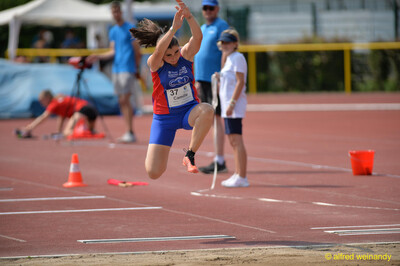 Eine junge Person fliegt über die Sandgrube beim Walfried-Heinz-Sportfest der TG Konz im Saar-Mosel-Stadion in Konz.