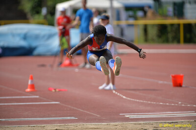Eine junge Person fliegt mit ausgebreiteten Armen über die Sandgrube beim Walfried-Heinz-Sportfest der TG Konz im Saar-Mosel-Stadion in Konz.