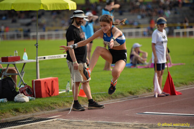 Eine jugendliche Person in der Landephase über der Sprunggrube im Weitsprung beim Walfried-Heinz-Sportfest der TG Konz im Saar-Mosel-Stadion in Konz.