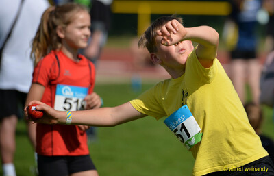 Ein Kind holt mit einem kleinen roten Schlagball zum Wurf aus bei der Rheinland-Meisterschaft im Mehrkampf der TG Konz in Konz.