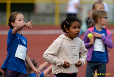 Mehrere Kinder stehen und warten auf der Bahn, ein Kind hält einen gelben Ball in der Hand, beim Jugendsportfest der TG Konz in Konz